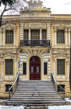 an old building with steps leading up to the front door and stairs down to the second floor