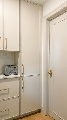 an empty kitchen with white cabinets and gold pulls on the door knobs is shown