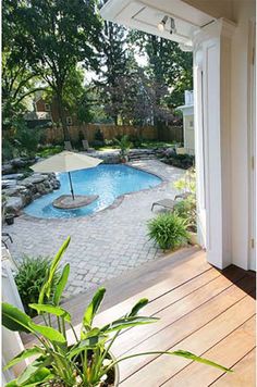 an outdoor swimming pool surrounded by greenery and wooden decking, with patio furniture