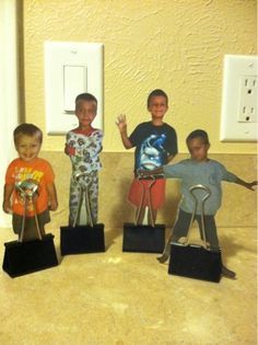 four children standing in front of three electrical outlets with their hands up and holding scissors