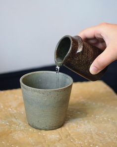 a person pouring water into a cup on top of a table