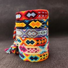 a stack of colorful bracelets sitting on top of a gray surface next to each other