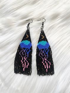 Get ready to make a splash with these hand beaded jellyfish fringe earrings. These earrings are a true underwater delight, featuring a stunning handcrafted jellyfish design adorned with intricate beadwork and delicate fringe. Teh combination of the jellyfish motif and the vibrant color of the beads create a mesmerizing accessory that captures the beauty of the ocean. Perfect for beach parties, summer events, or simply embracing your love of marine life. Don't miss out on these unique earrings that will add a touch of whimsy and elegance to any outfit. Dive into style and let your creativity flow with these amazing jellyfish earrings.  *Features: set of two (2) nickel free fish-hook style earring with rubber backing *Hand beaded  *High quality materials *Measures approximately 3.5in x 1.25 Whale Beaded Earrings, Handmade Unique Drop Tassel Earrings, Handmade Unique Tassel Drop Earrings, Unique Handmade Tassel Drop Earrings, Unique Handmade Dangle Tassel Earrings, Whimsical Adjustable Beaded Earrings, Adjustable Beaded Fringe Jewelry Gift, Adjustable Beaded Fringe Jewelry As Gift, Unique Long Drop Beaded Earrings As A Gift