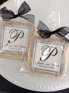 two cookies wrapped in cellophane and tied with black ribbon are sitting on a plate