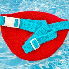 a red and blue knitted hat sitting on top of a swimming pool