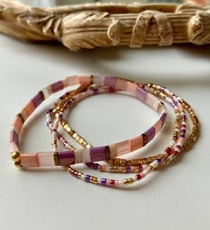 three beaded bracelets sitting on top of a table next to a wooden stick