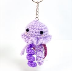 a crocheted octopus keychain hanging from a metal hook on a white background