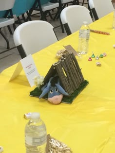 the table is set up with yellow cloths and plastic chairs, which have decorations on them