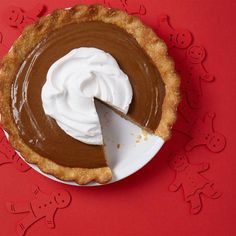 a pie with a slice taken out of it on a red table top next to the rest of the pie