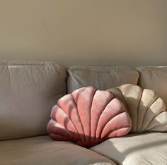 a shell shaped pillow sitting on top of a couch next to a white sofa cushion