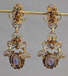 "Vintage 1960s era signed Celebrity by Juliana statement earrings. These are such beautiful and ornate earrings. Earrings feature glass cameos prong set in filigree goldtone with citrine rhinestones also prong set. Earrings are clip back style. Earrings are fully hallmarked and will arrive gift boxed. MARKS Celebrity on clip backs. CONDITION In very good to excellent condition. Please use all pictures as part of item's description. SIZE  2 7/8\" x 1 1/4\". MATERIALS Glass, Goldtone, Rhinestones. Vintage Clip-on Earrings For Evening, Victorian Earrings For Pierced Ears For Party, Victorian Style Earrings For Party, Vintage Antique Gold Drop Earrings, Antique Gold Vintage Drop Earrings, Vintage Formal Filigree Chandelier Earrings, Vintage Formal Earrings, Vintage Gold Earrings For Evening, Victorian Dangle Chandelier Earrings For Parties