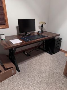 a desk with a computer on top of it in a room filled with cardboard boxes