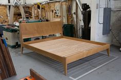 a wooden bed frame in a room with tools