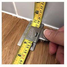 a person measuring the width of a wall with a tape measure