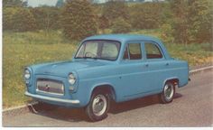 an old blue car is parked on the side of the road