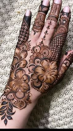 a woman's hand is decorated with hennap and flower designs on it