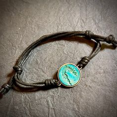 This beautiful Cherokee Nation bracelet is a unique piece of jewelry that embodies the spirit of the tribe. Crafted with a metal bezel and engraved wood, it is a stunning piece that is perfect for any occasion. The slip cord design adds a touch of rustic to the bracelet, making it a must-have for any jewelry collection. The bracelet is perfect for those who love nature, regional, and tribal jewelry, and it is sure to be a conversation starter wherever you go. Casual Metal Jewelry With Adjustable Cord, Adjustable Turquoise Nature-inspired Jewelry, Turquoise Symbolic Adjustable Jewelry, Adjustable Nickel-free Bracelets With Waxed Cord, Adjustable Nature-inspired Bracelet Jewelry, Adjustable Nature-inspired Jewelry Bracelet, Nature-inspired Adjustable Bracelet Jewelry, Adjustable Nature-inspired Bracelet, Nature-inspired Adjustable Round Jewelry