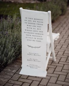 a white chair sitting on top of a brick walkway next to lavender plants and flowers