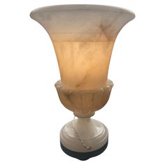 a white vase sitting on top of a wooden table next to a light brown base