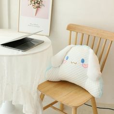 a laptop computer sitting on top of a wooden chair next to a table with a stuffed animal