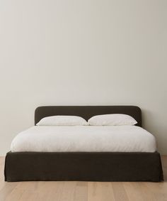 a bed sitting on top of a hard wood floor next to a white wall in a bedroom