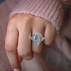 a close up of a person's hand with a diamond ring on their finger