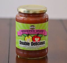 a jar of grandma's grand apple sauce sits on a wooden table with the lid open