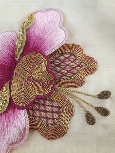 a pink flower with gold accents on a white cloth background is featured in this close up photo