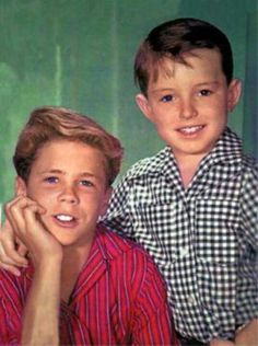 two young boys are posing for a photo in front of a green background and one boy is smiling at the camera