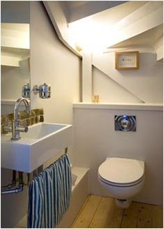 a white toilet sitting next to a sink in a bathroom under a slanted ceiling