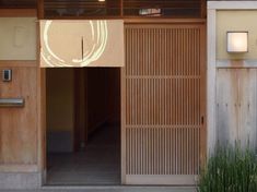 an entrance to a building with wooden doors and plants in the foreground on either side