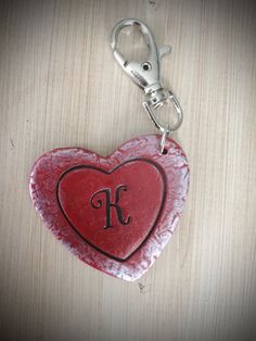 a red heart shaped keychain with the letter k on it's side