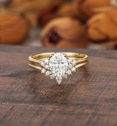 an engagement ring with a pear shaped diamond in the center on top of a wooden table