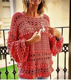 an older woman wearing a red crocheted sweater and holding something in her hand