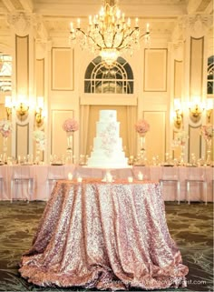 a white wedding cake on top of a table with pink flowers and candles in front of it