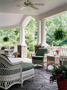 a covered porch with wicker furniture and potted plants