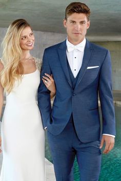 a man in a blue suit and woman in a white dress standing next to each other