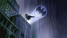 batman flying in the sky over a city at night with rain falling down on it