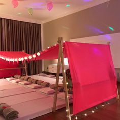 a bed with pink sheets and lights on it