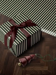 a present wrapped in black and white striped paper with a red ribbon on it sitting on a wooden floor