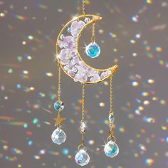 an image of a crescent moon with jewels hanging from it's side and stars in the background