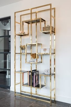 a book shelf with books on it in front of a white wall and black tile floor