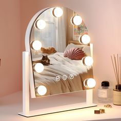 a lighted vanity mirror with an image of a cat laying on the bed in front of it