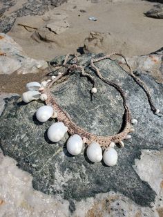 a necklace made out of shells sitting on top of a rock