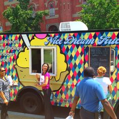 a woman standing in front of a colorful ice cream truck on the side of the road