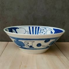 a blue and white bowl sitting on top of a wooden table next to a wall