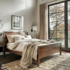 a bedroom with a bed, dresser and large window overlooking the trees in the distance