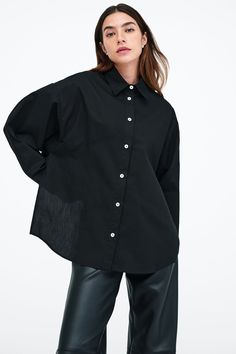 Our Ezra Shirt is a capsule wardrobe dream for your closet. Crafted from 100% crisp European poplin cotton, she offers a classic button-up silhouette in front, but with a cropped back for modern edge. Say hello, as well, to her diagonal seams at the front, sleek collar and long dolman sleeves finished with mother-of-pearl button cuffs. Wear Ezra tucked, tied or open and free—she never fails to inspire new looks.[SPLIT] Rocio, in black and in light blue, is 5'9.5" (175 cm) tall, wearing size XS. Elevated Streetwear, Black Button Up Shirt, Black Shirts Women, Tunic Hoodie, Design Boards, Front Tie Shirt, Simple Wallpapers, New Looks, Dolman Sleeve