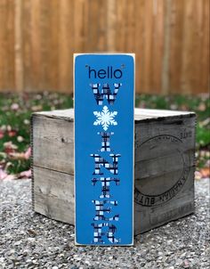 a wooden sign that says hello winter on it's front and back side, with snowflakes in the background