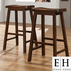 two wooden stools sitting on top of a hard wood floor next to a window